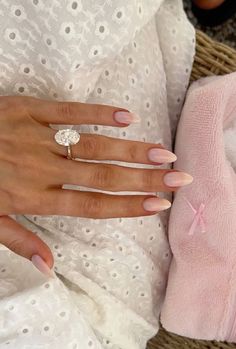 a woman's hand with pink and white manicured nails holding a diamond ring