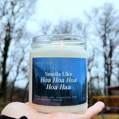 a hand holding a jar of hoa haa with trees in the background