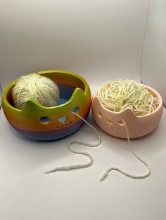 two bowls with yarn in them sitting on a white counter top next to each other