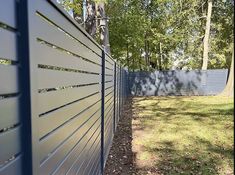 a white fence in the middle of a park with trees and grass on both sides