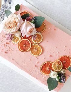 there is a pink cake with oranges and flowers on it