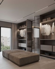 a walk in closet with an ottoman and clothes on hangers