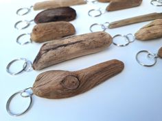 several pieces of driftwood and metal chains on a white surface with silver rings hanging from them