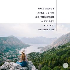 a woman sitting on top of a rock looking out over a valley