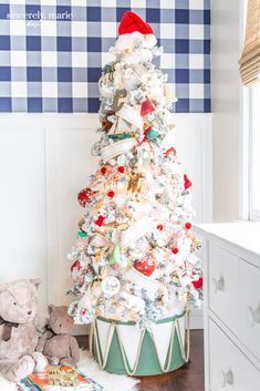 a white christmas tree sitting in the corner of a room next to a teddy bear