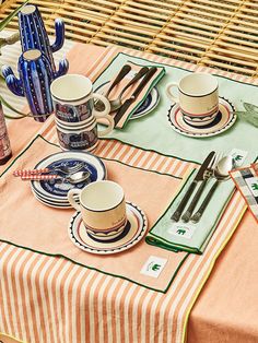 the table is set with two cups and saucers, silverware and utensils