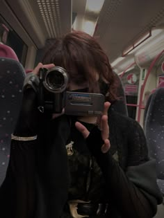 a woman holding up a camera to take a photo on a train with her phone