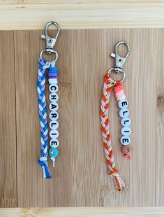 three personalized key chains with name tags attached to them on a wooden surface,