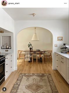 a kitchen with an archway leading to the dining room and living room, along with a large rug on the floor