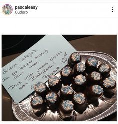 there are chocolates with blue and white frosting on the plate next to a note