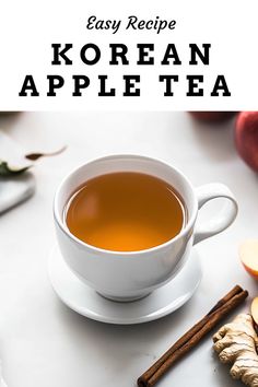 a cup of korean apple tea next to sliced apples and cinnamon sticks on a white table