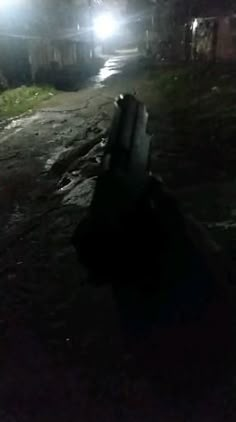 a bench sitting on the side of a dirt road at night with headlights shining down