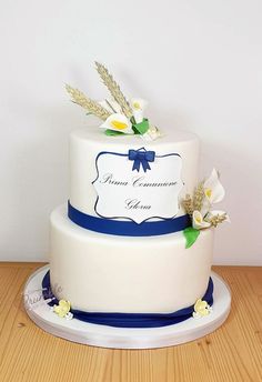 a white cake with blue ribbon and flowers on top