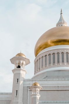 a large white and gold dome on top of a building with two towers in front of it