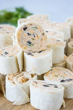 several rolls are stacked on top of each other with vegetables in the background and one roll has been rolled up