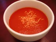 a white bowl filled with tomato soup on top of a wooden table