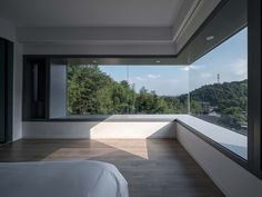 an empty bedroom with large windows overlooking the trees and hills in the distance is shown