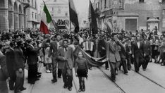 a group of people walking down a street with flags and banners in the middle of them