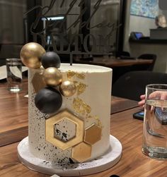 a white and gold cake sitting on top of a wooden table