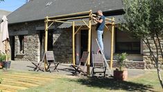 a man standing on top of a wooden structure in front of a building with windows