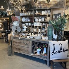 an old wooden table with plates and vases on it in a room filled with other items