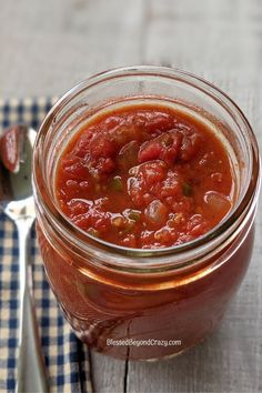 a glass jar filled with food sitting on top of a table next to a fork