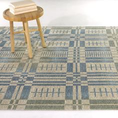 a wooden stool sitting on top of a rug next to a table with two books