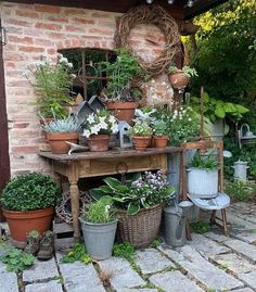 an outdoor garden area with potted plants on the table and other items around it