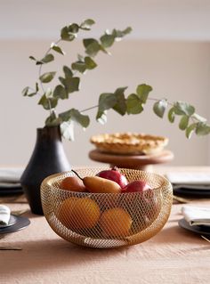 a bowl filled with fruit sitting on top of a table next to other plates and utensils