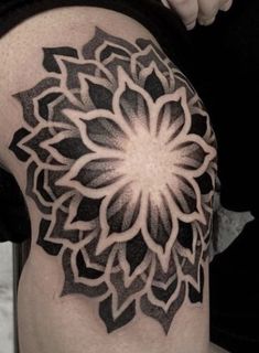 a black and white photo of a woman's thigh with a flower tattoo on it