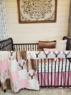 a baby crib with pink, brown and white bedding in front of a painting on the wall