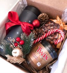 an open box filled with assorted items and wrapped in red ribbon, pine cones, candy canes