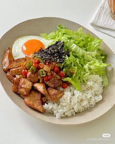 a plate with rice, lettuce, and an egg on it next to a glass of water