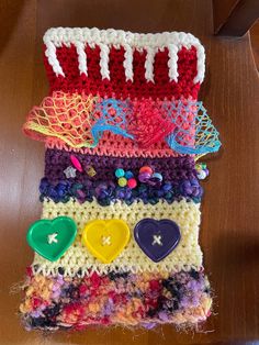 a crocheted piece of cloth with buttons and other things on it sitting on a table