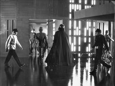 black and white photograph of people dressed as darth vader walking down the hall