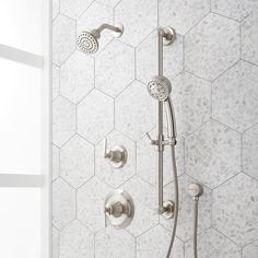 the shower head and handset are shown in this bathroom setting with hexagonal tiles