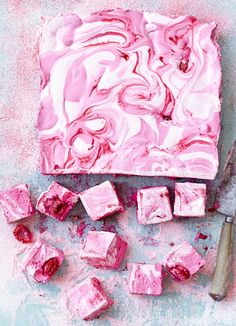 pink swirled cake sitting on top of a table next to a spatula and knife