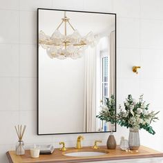 a bathroom sink with a mirror above it and vases on the counter next to it