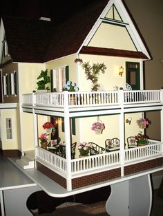 a doll house is shown with flowers on the balcony and balconies on the second floor