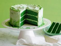 a green cake with white frosting and sprinkles sitting on a plate