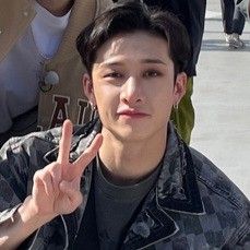 a young man is making the peace sign with his hand while standing in front of other people