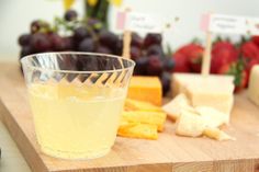 cheese, crackers and grapes on a cutting board with a glass of wine in the foreground