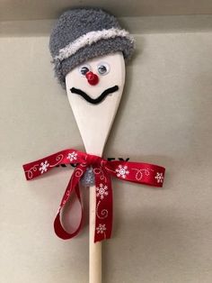 a wooden spoon decorated like a snowman with a hat and scarf on it's head