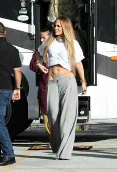 a woman in grey pants and white shirt standing next to a bus