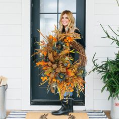 a woman standing in front of a door holding a wreath