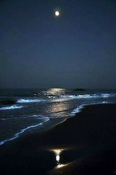 the moon shines brightly in the night sky over an ocean with waves and sand