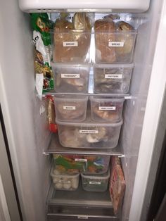 the refrigerator door is open with plastic containers and food items in it's bottom shelf