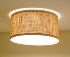 a lamp shade hanging from the ceiling in a room with white walls and flooring