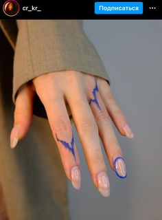 a woman's hand with blue and white designs on her fingers, holding onto the ring finger