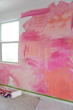 a large pink painting on the wall in a room with white paint rollers next to it